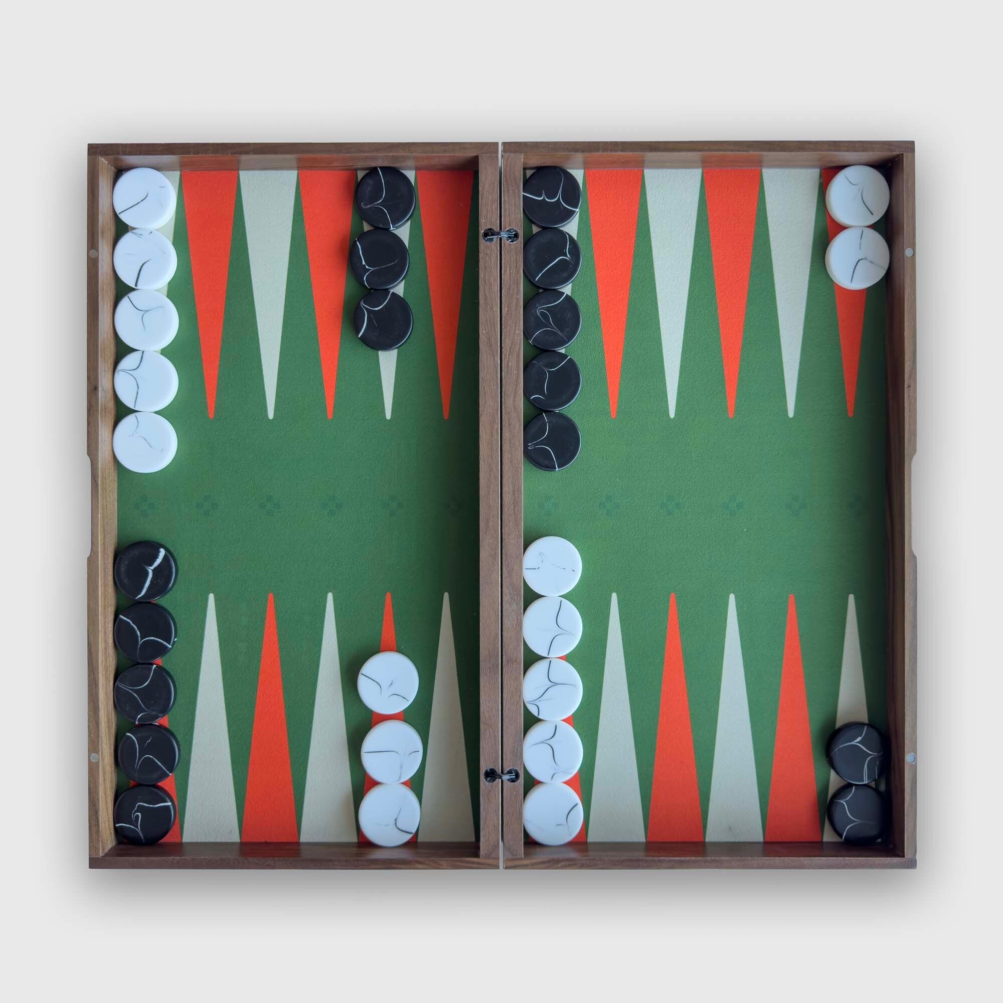 A "PRIME" backgammon board set shown open and centered against a plain light background. The board has a green field with alternating orange and white triangles, black and white checkers, and a medium brown wood frame.