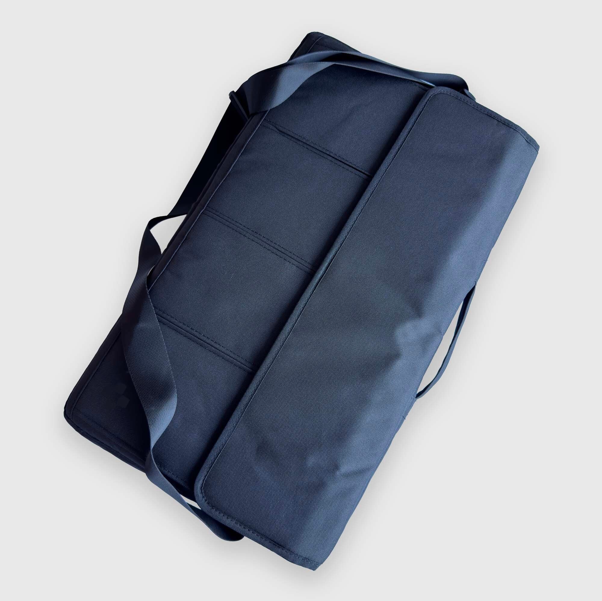 A dark navy blue rectangular bag for the "PRIME" backgammon board with a long shoulder strap, shown from an overhead angle on a light gray background.