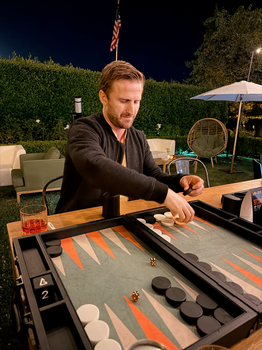 Player moving checkers on a Nova board at an evening game
